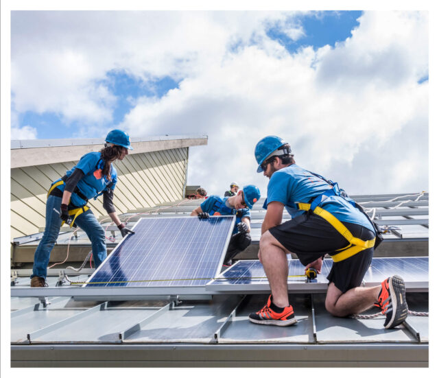 Foto de tres trabajadores instalando paneles solares en un techo